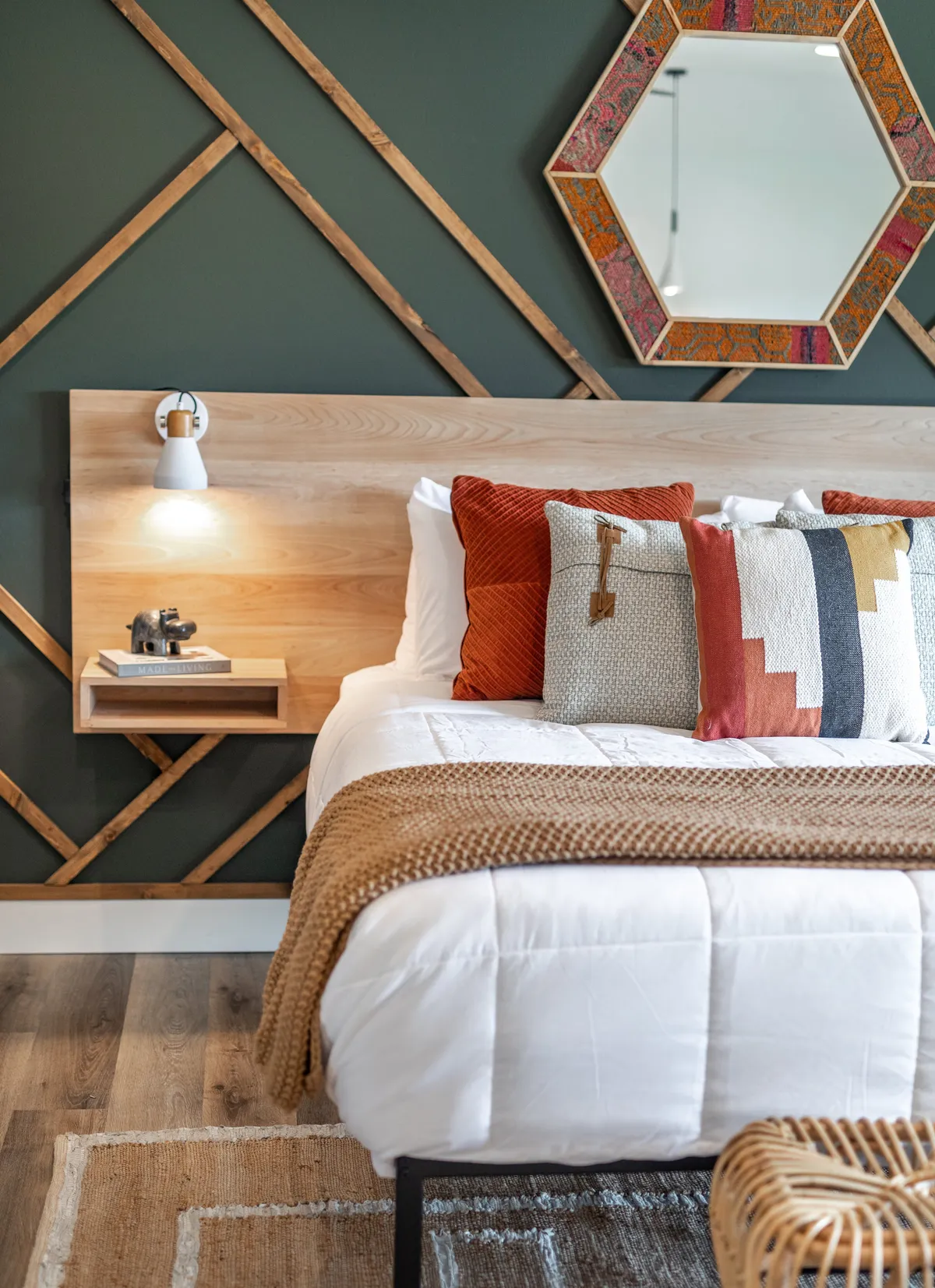A cozy bedroom with a wooden headboard, decorative pillows, a nightstand lamp, a woven throw blanket, and a soft rug. The space is bathed in warm light, exuding comfort and warmth—perfect for winding down after an adventurous day.