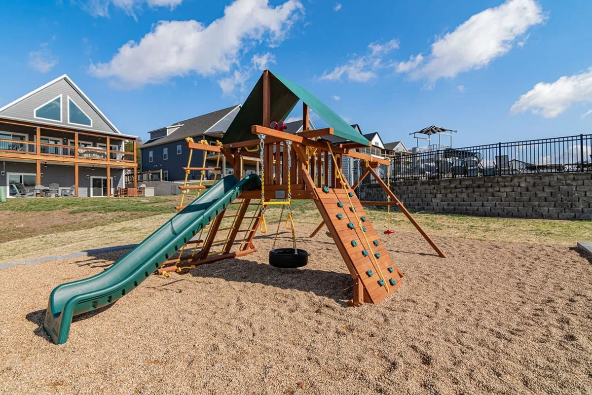 A joyful playground with a slide and swing set, set amongst greenery. The area is clearly designed for children to play and families to gather, exuding a sense of community and fun.
