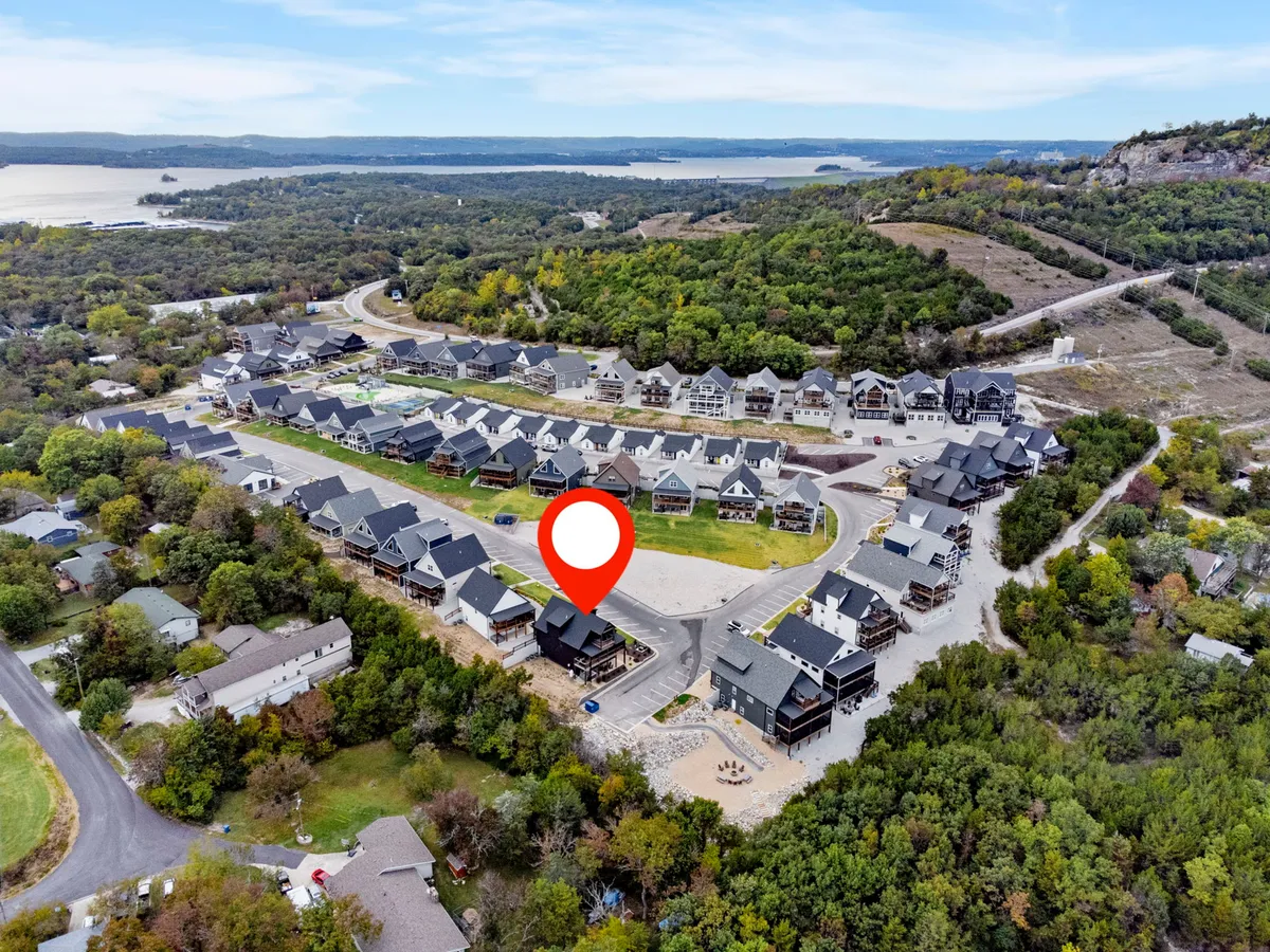 A sweeping aerial shot of a residential community nestled by a lake, surrounded by lush greenery and scenic views. The image captures the cul-de-sac layout, blending peaceful residential living with easy access to outdoor recreation and local attractions.
