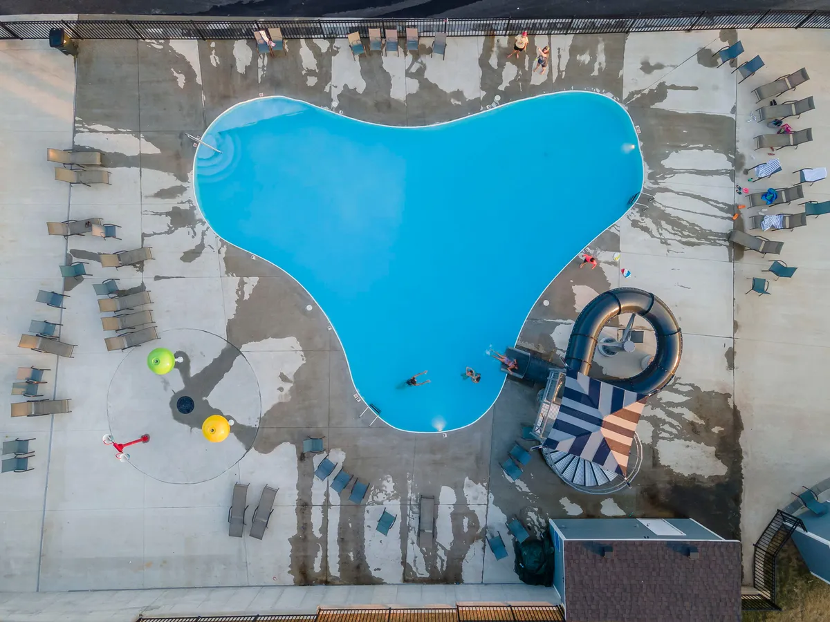 This exterior image showcases a vibrant swimming pool area complete with a water slide, lounge chairs, and colorful pool toys. The scene is lively, filled with the sense of summer fun and family enjoyment, emphasizing outdoor recreation and relaxation.