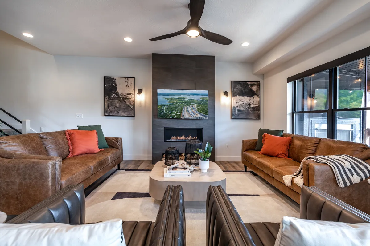 A welcoming living room scene featuring leather sofas grouped around a modern coffee table, a wall-mounted TV, a glowing fireplace, and curated wall art. The space radiates comfort and encourages relaxation and togetherness.