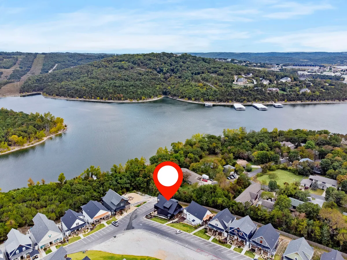 An aerial perspective showing the lodge marked with a red marker near a winding river, surrounded by lush hills. The image highlights both the property’s location and its easy access to the water’s edge.