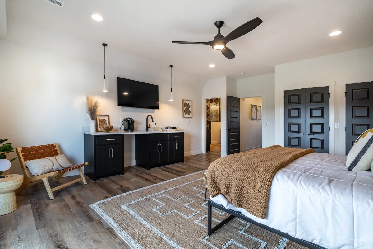 A spacious bunk room designed for kids, featuring a bed, a small kitchenette, seating area, rug, and a television. The space is cheerful and practical, perfect for young guests to relax, play, or enjoy movie nights together.