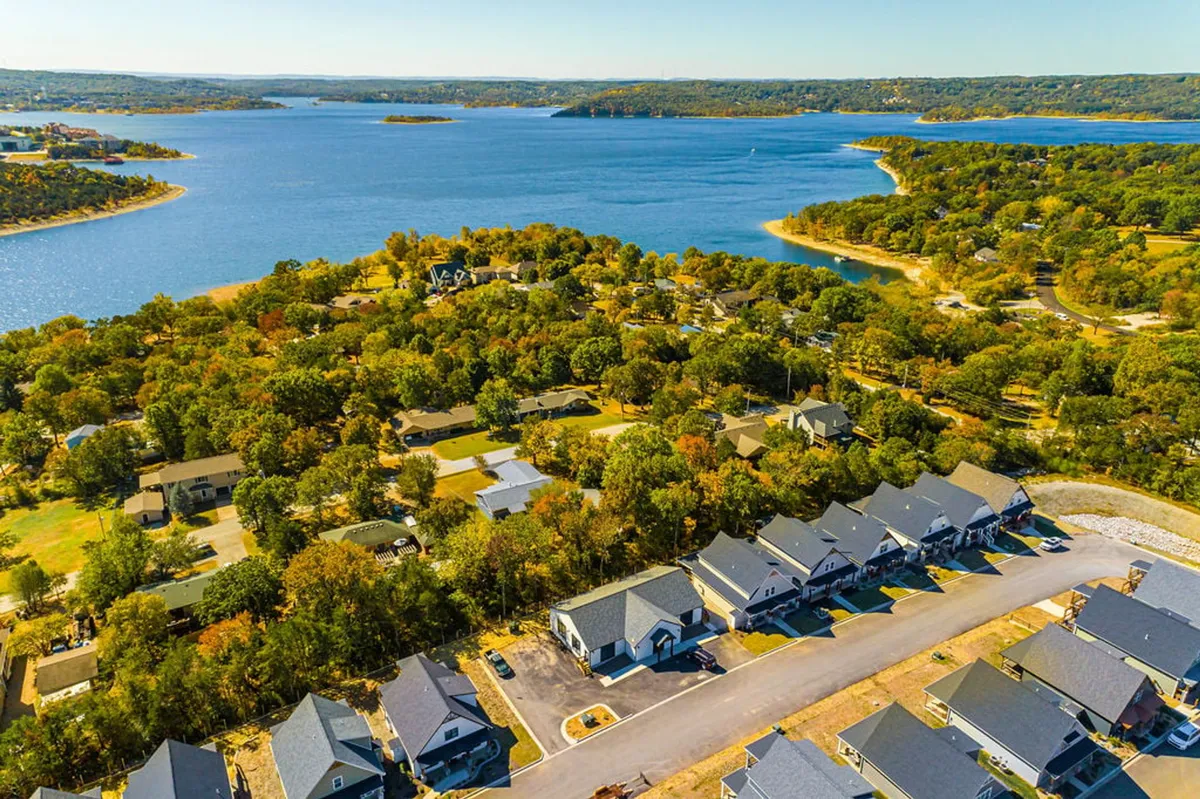 A panoramic view of the lake with nearby homes nestled among hills and trees. The calm water sets the scene for boating, fishing, and family picnics along the shore.