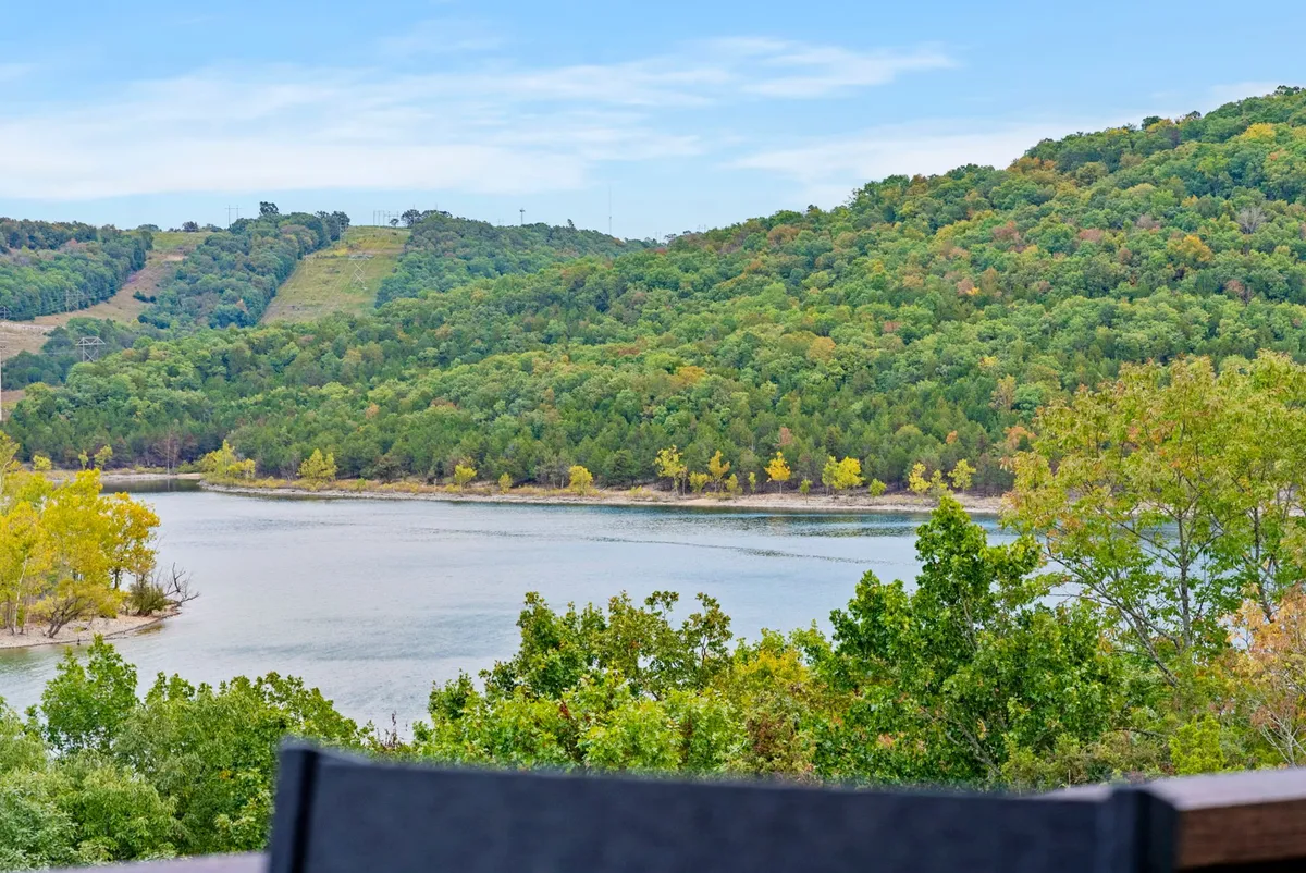 A tranquil view of Table Rock Lake, framed by rolling hills and trees. The water glistens under the sunlight, creating a serene and inviting atmosphere perfect for outdoor adventures.